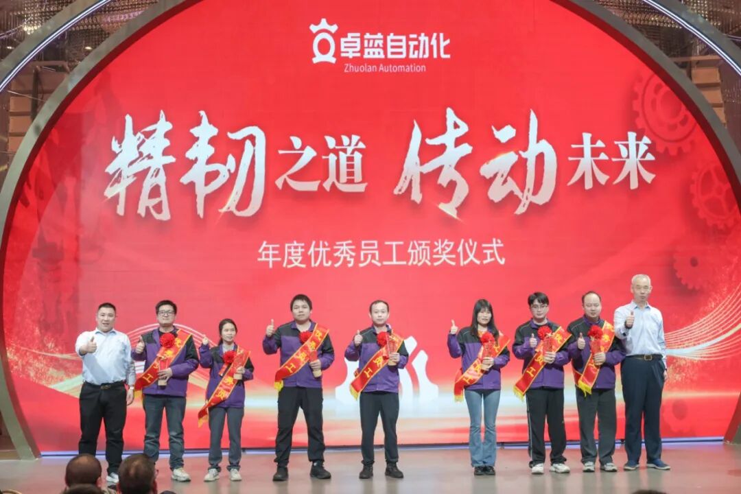 Eight people stand on stage in front of a large red screen, posing after an awards ceremony.