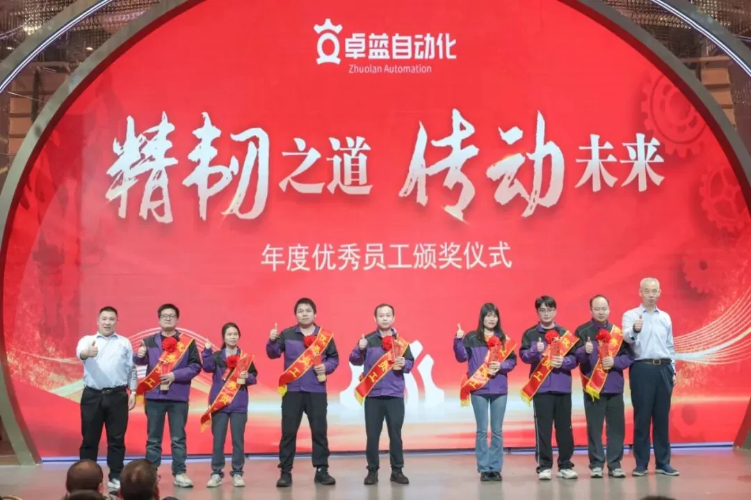 Eight people stand on stage in front of a large red screen, posing after an awards ceremony.