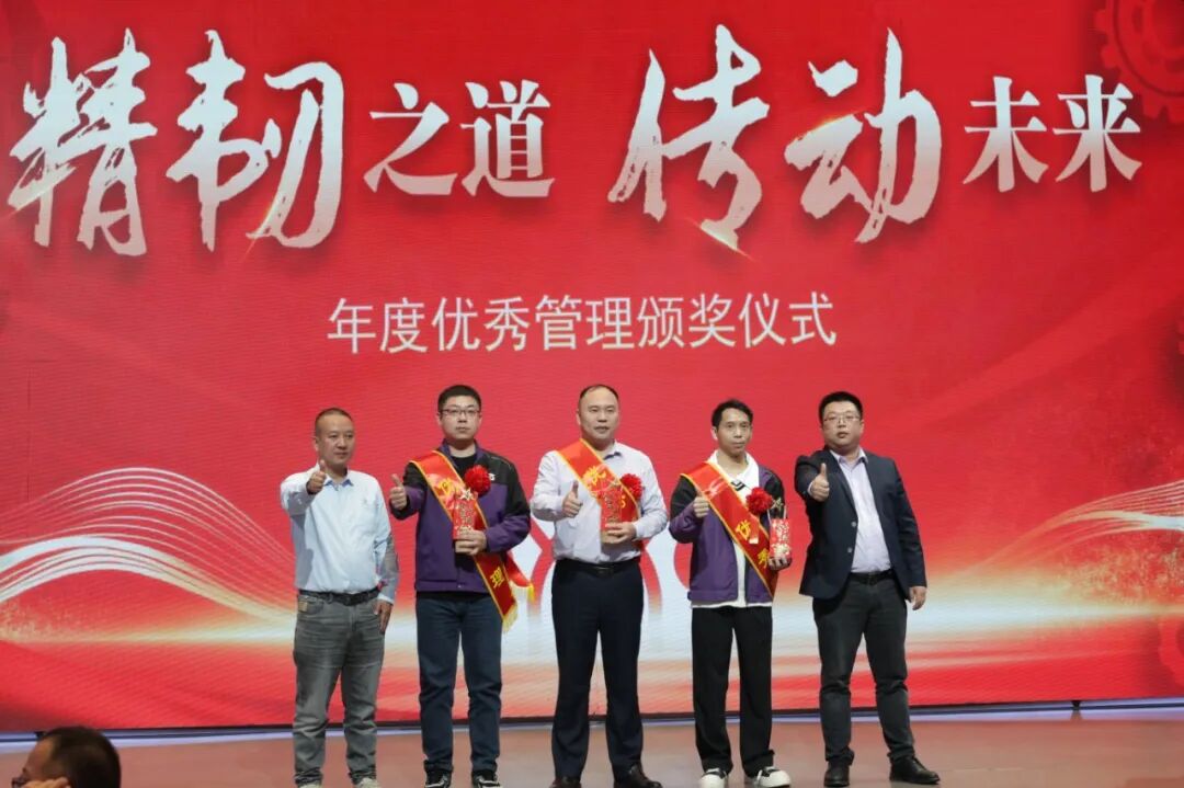 Five men stand on stage against a large red backdrop during what appears to be an awards ceremony.