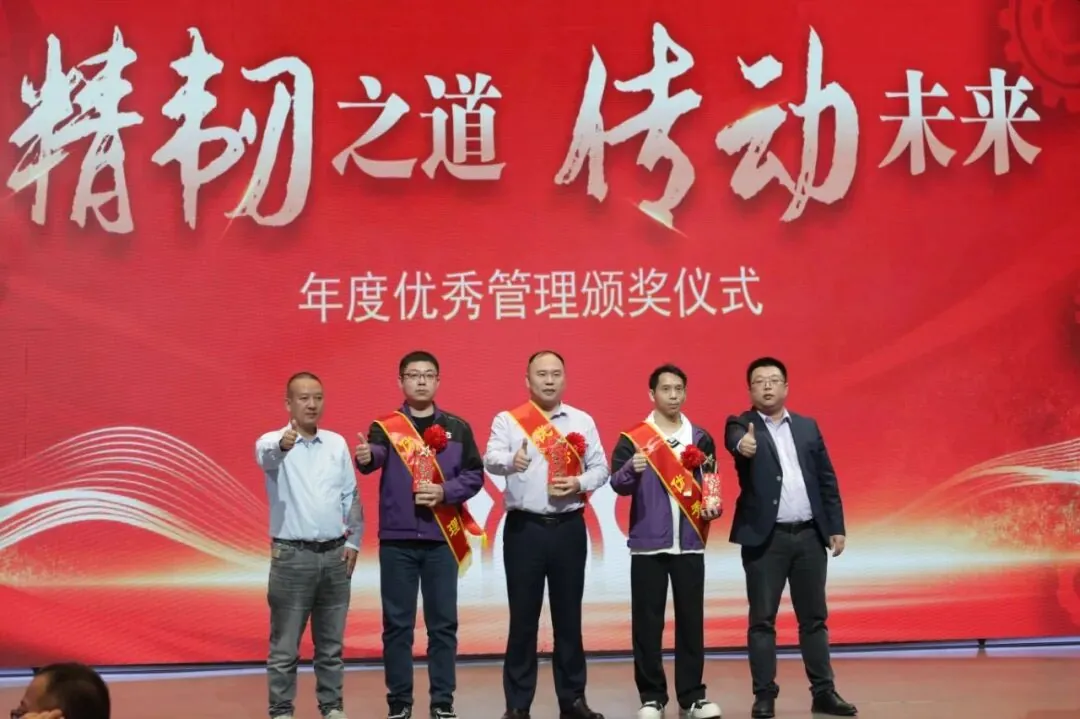 Five men stand on stage against a large red backdrop during what appears to be an awards ceremony.
