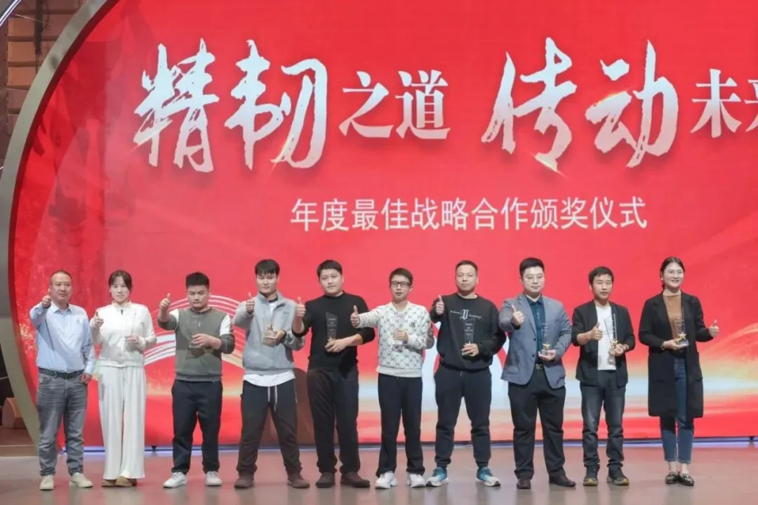 Ten people pose on stage with awards against a large red screen with stylized white text.
