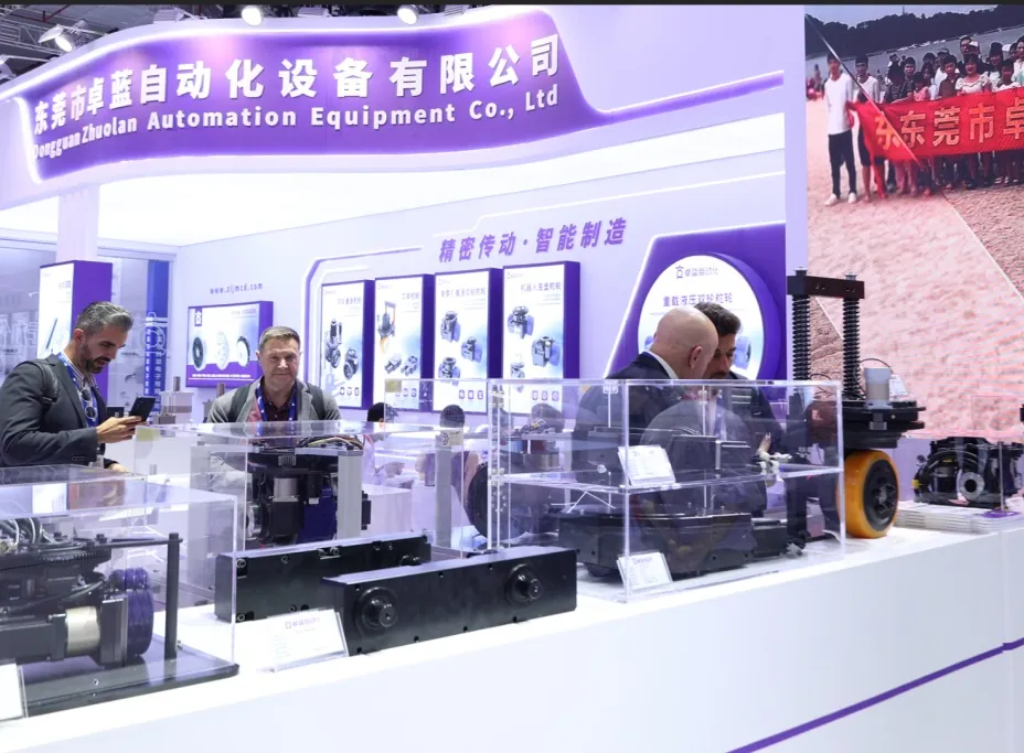 Visitors examining AGV steering drive wheels in acrylic cases at a purple Zhuolan exhibition booth.