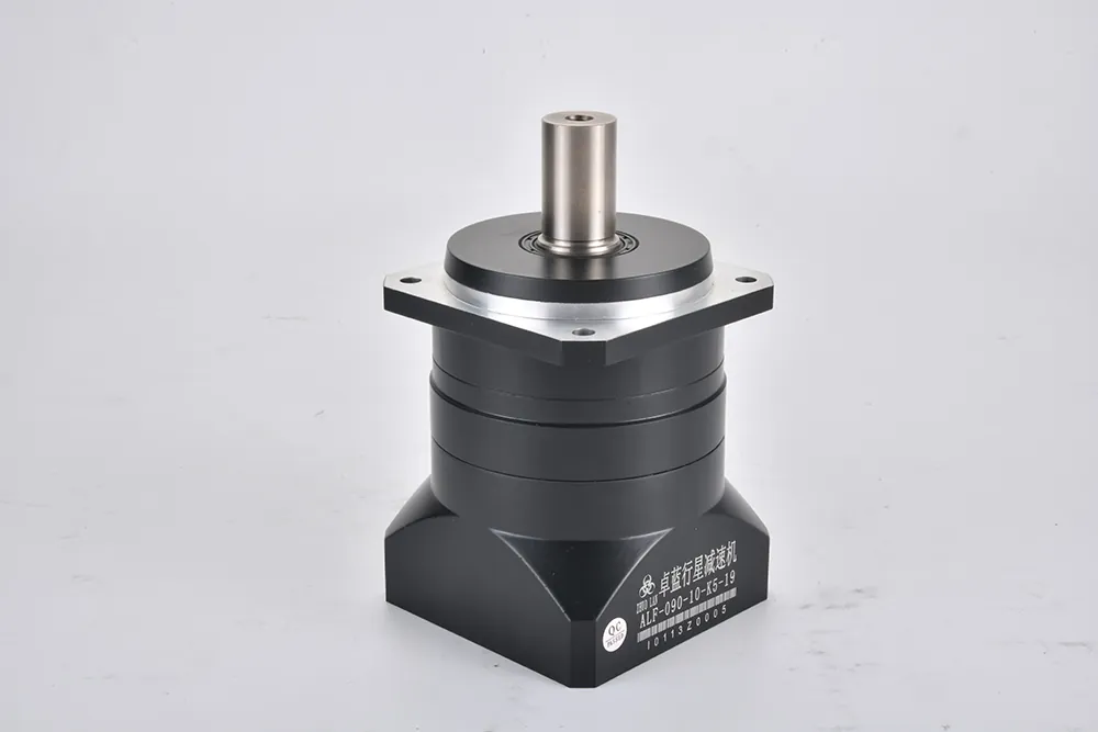 A black planetary gearbox stands upright on a white surface. It features a silver mounting flange and a polished output shaft. A label on the side reads "ALF-090-10-K5-19 1011320005".