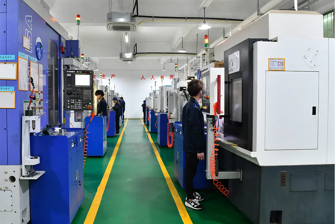 Workers operate CNC machining centers along an industrial production line in a modern manufacturing facility.