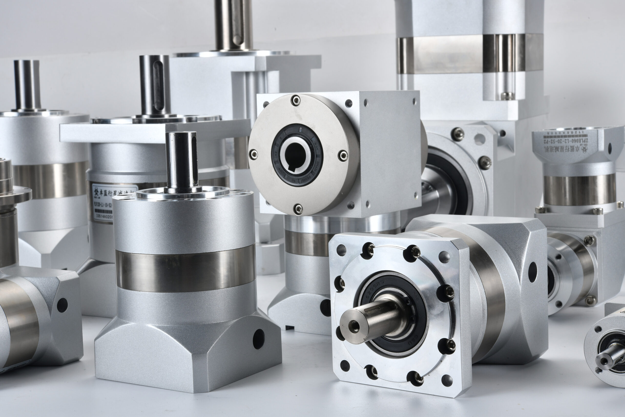 A collection of silver and gray industrial gearboxes and reducers of various shapes and sizes, with some showing product labels.