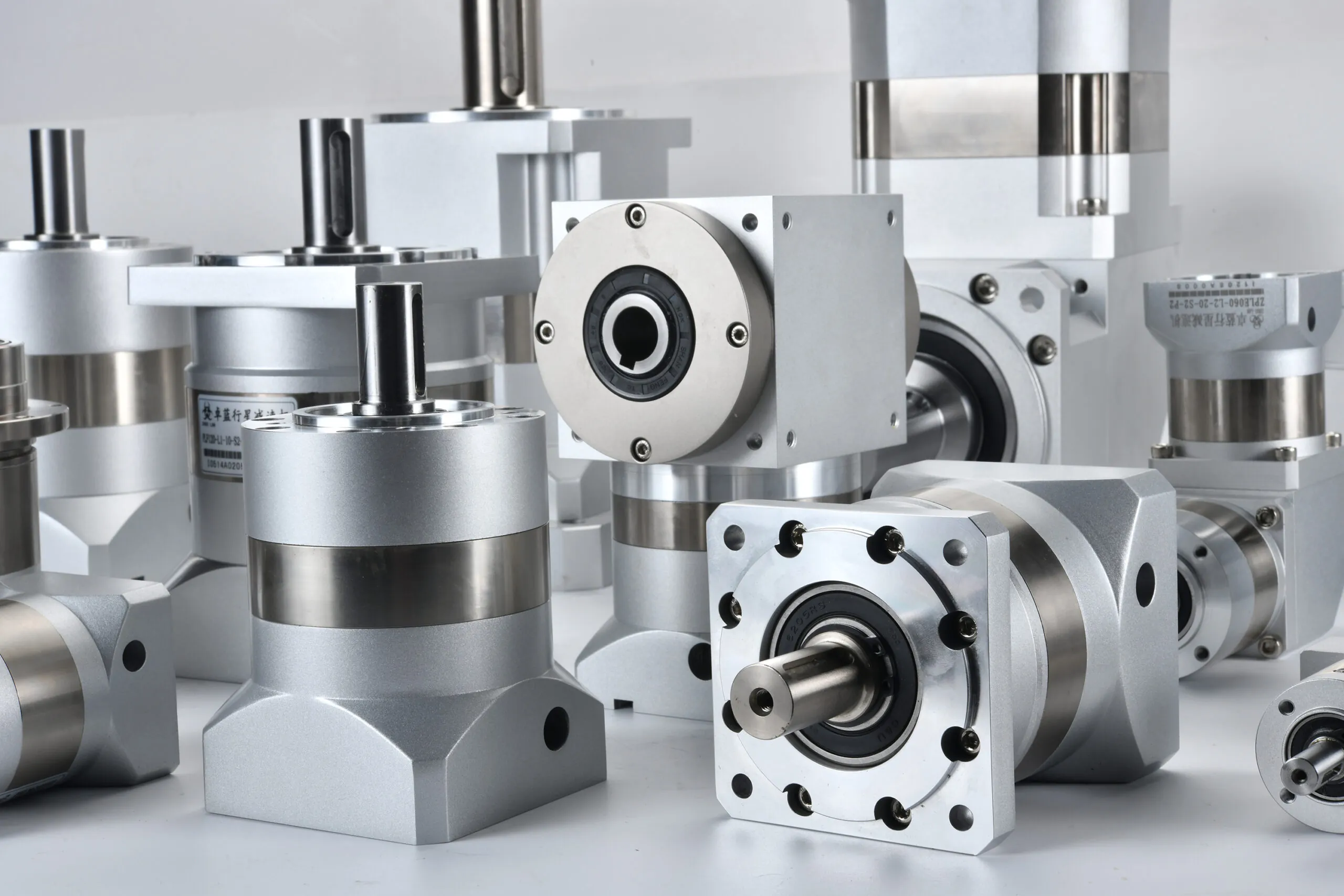 A collection of silver and gray industrial gearboxes and reducers of various shapes and sizes, with some showing product labels.