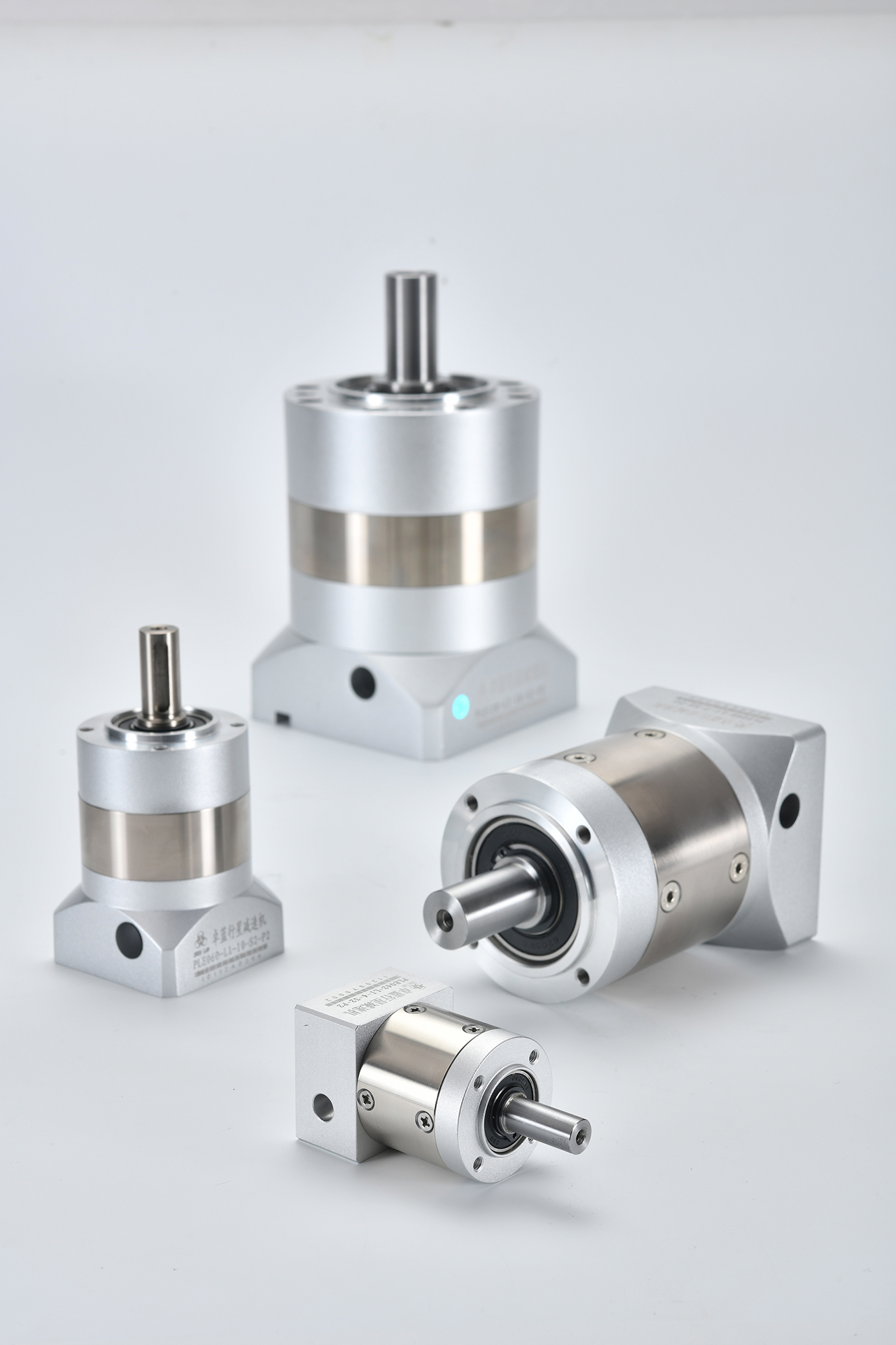 Four silver planetary gearboxes of varying sizes and configurations, including inline and right-angle models, with visible shafts and mounting holes.