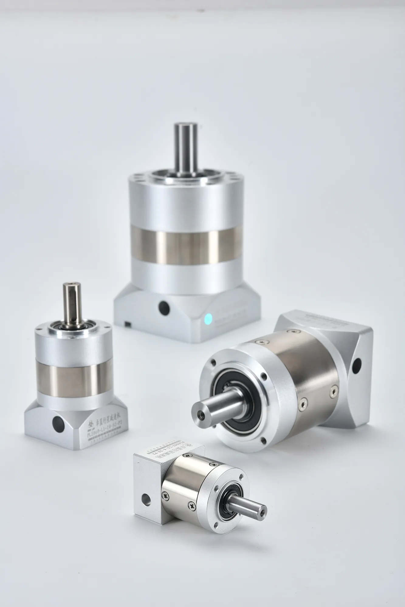 Four silver planetary gearboxes of varying sizes and configurations, including inline and right-angle models, with visible shafts and mounting holes.