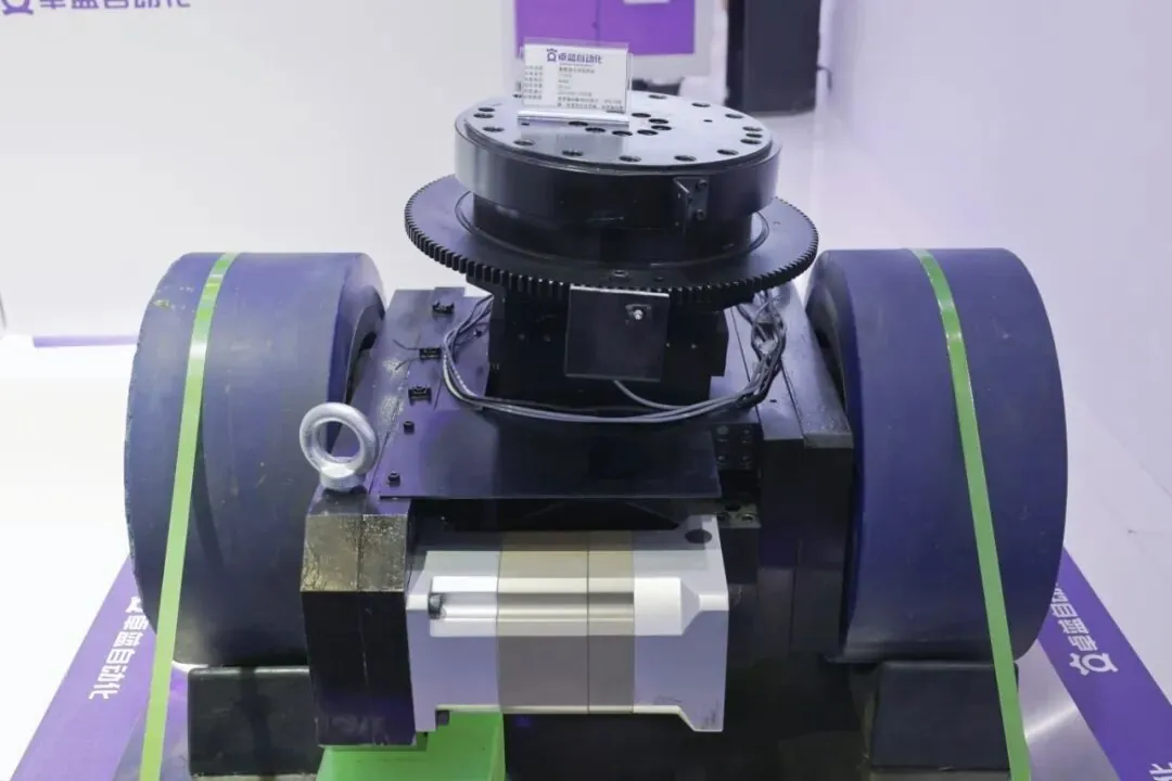 Một bộ phận dẫn động bánh đôi AGV hạng nặng với lốp polyurethane lớn màu tím và một vòng răng gắn trên đỉnh.