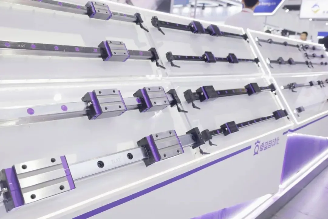 Precision linear guide rails with sliding blocks displayed on angled shelves at a trade show booth.